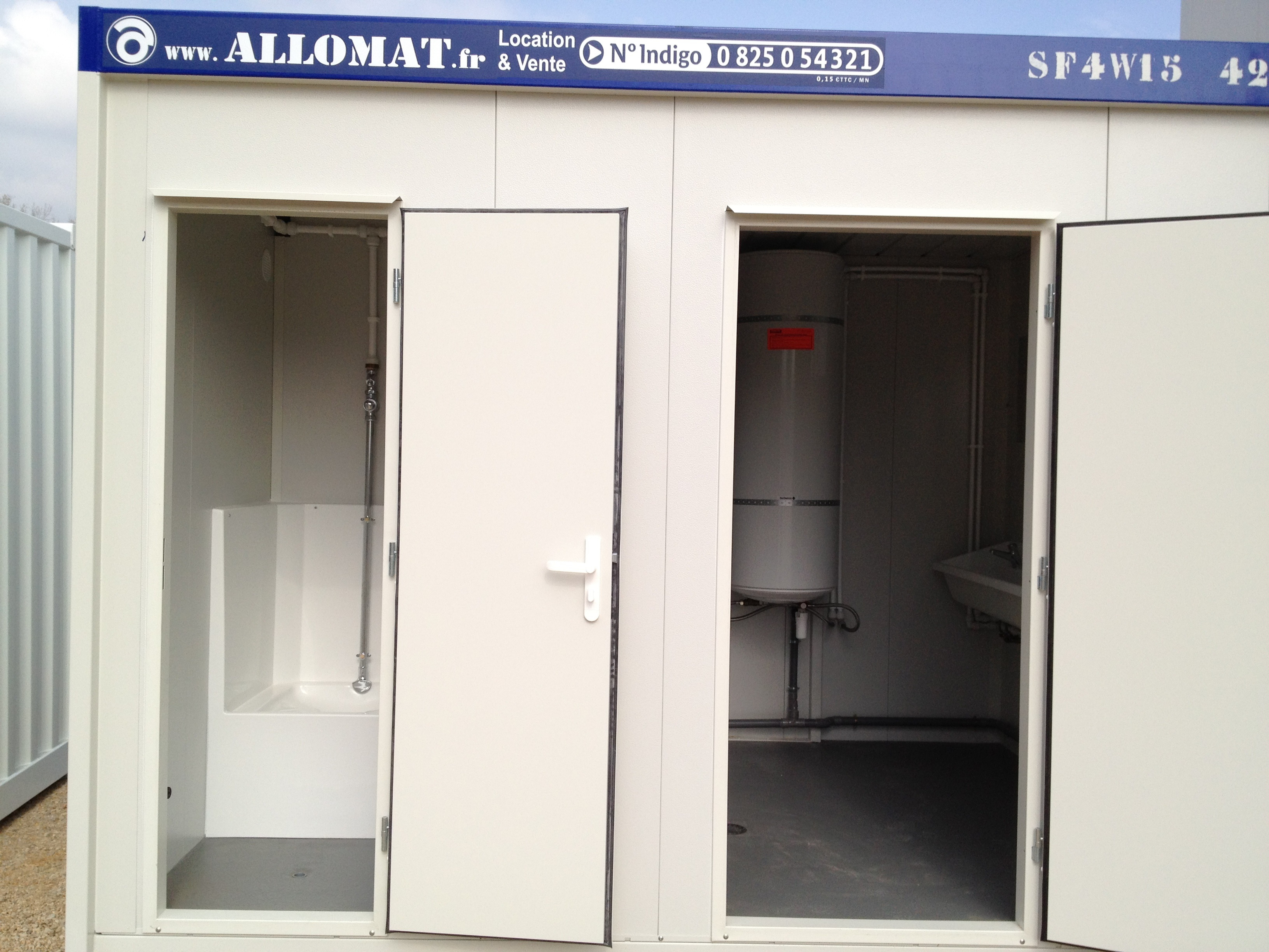 Un bungalow sanitaire avec 2 portes ouvertes, celle de gauche qui donne sur un WC à la turque et celle de droite sur un chauffe-eau 200L, avec à gauche un lavabo et une douche.
